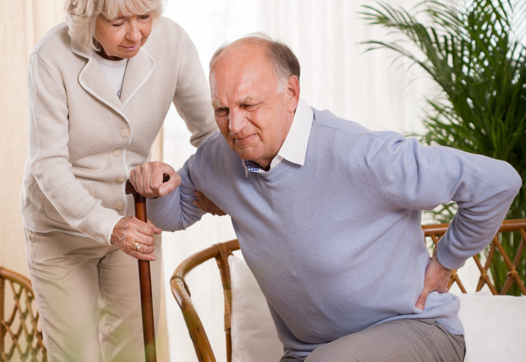 Woman helping an elderly man having a back pain